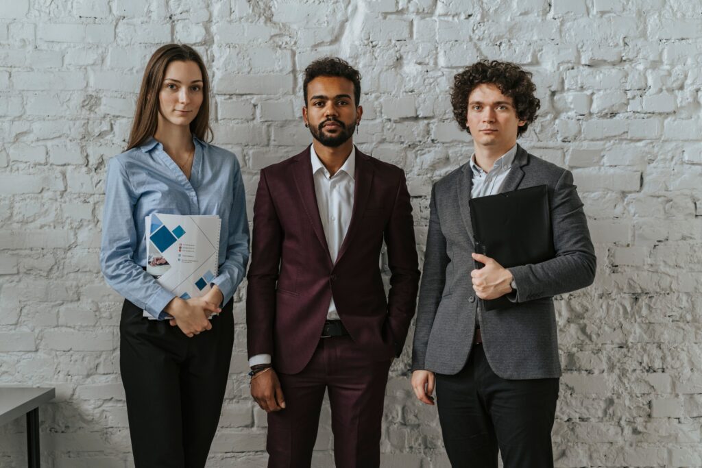 Three business professionals standing confidently in an office setting.